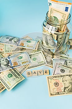 Money in international currency, including the euro, the dollar lies on a blue background next to a jar with banknotes