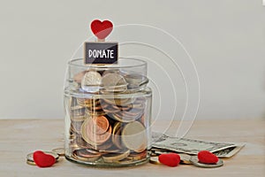 Money jar full of coins with Donate label and hearts - Charity concept