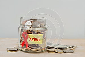 Money jar full of coins with red ribbon and Donate label - Aids charity and research fund concept