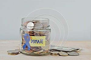 Money jar full of coins with violet ribbon and Donate label - Concept of prostate cancer charity and research fund