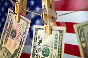 Money laundering with US dollars hung out to dry on American flag background. Dollar bills hanging on clothesline, close