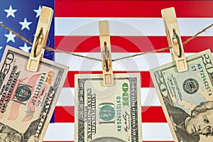 Money laundering with US dollars hung out to dry on American flag background. Dollar bills hanging on clothesline, close