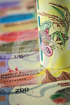 Money from Madagascar, 20,000 ariary banknote rolled up and lying on the rest of the currency