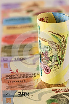 Money from Madagascar, 20,000 ariary banknote rolled up and lying on the rest of the currency