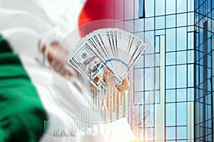 Money in a man`s hand against the background of the flag of Mexico. Income of Mexicans. The financial condition of the people of