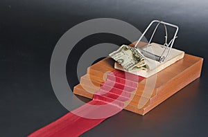 Money in a mousetrap on the red carpet and black background.