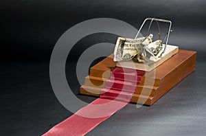 Money in a mousetrap on the red carpet and black background.