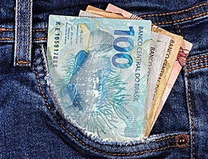 money notes from brazil in jeans pocket. money from brazil. earn money. Real, Currency, Money, Dinheiro, Reais, Brasil. photo