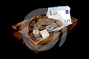 Money in an old box, banknotes and coins, isolated on black