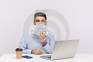 Money online! Angelic happy rich businessman with nimbus on head peeking out of dollar banknotes