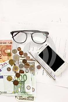 Money phone calculator pen paper and glasses on white background