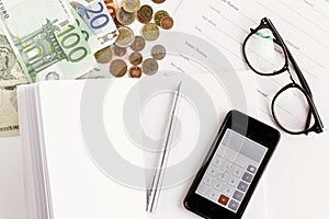 Money phone calculator pen paper and glasses on white background