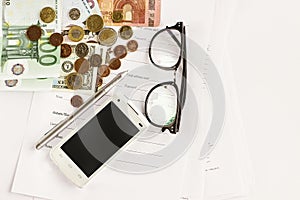 Money phone calculator pen paper and glasses on white background