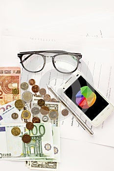 Money phone calculator pen paper and glasses on white background