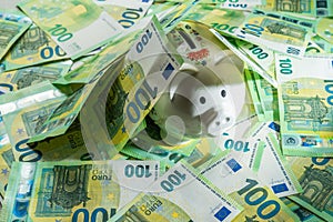 Money pig on the background of money bills of 100 euros, center ange view on piggy bank covered with money banknotes