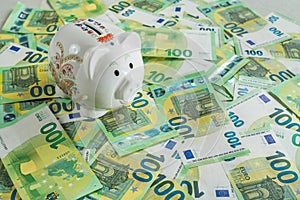 Money pig on the background of money bills of 100 euros, left agle view on piggybank