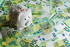 Money pig on the background of money bills of 100 euros, left angle view on piggy bank with shadow