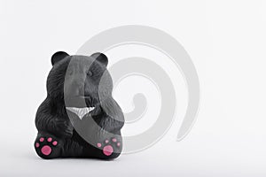 money piggy bank in the form of a black bear made of clay on a white background.