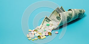 Money and pills of different colors on a blue background. The rise in the cost of medical care. The concept of insurance