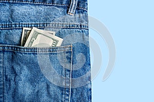 Money in pocket. One hundred dollar bill in a pocket of blue jeans on a blue background. Copy space. Concept of earning and saving