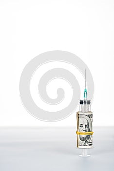Money roll and syringe on grey surface isolated