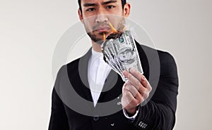 Money is the root to all evil. Studio shot of a young businessman burning a banknote against a white background.