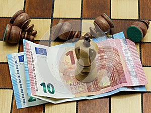 Money Rules Concept: King Chess Piece On Euro Banknotes With Defeated Pawns