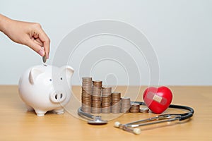 Money Saving, Health Insurance, Medical, Donation and Financial concepts. hand putting coin into piggy bank with stethoscope and