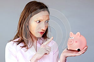 Money savings stressed woman holding moneybox pink piggy bank