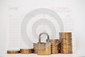 Money and Security Concept. Gold master key lock with stack of coins on bank passbook