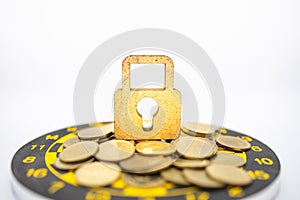Money, Security, Target and Goal Concept. Close up of wooden master key lock icon on pile of gold coins on black and yellow dart