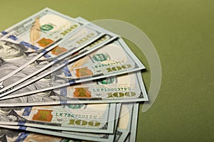 Money, stacks of US hundred dollar bills on an olive background.