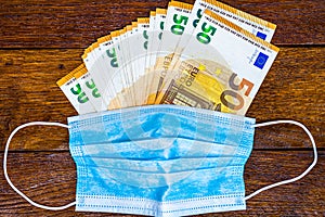 Money with surgical mask on wooden table. Flu disease virus spreading in Europe, virus protection methods concept. Changes and