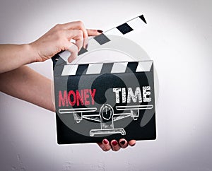 Money and Time Balance. Female hands holding movie clapper