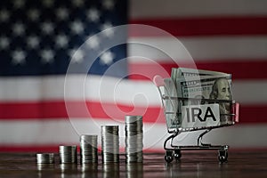 Money towers and shopping cart used for saving US dollar bills and notes for IRA retirement fund on the American flag background,