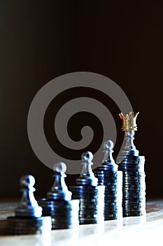 Money is a true king. Chess pawn stand on the highest coin stack wearing a crown. Wealthiness concept