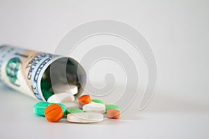 Money from the United States with vibrantly colored medicines on a neutral white background. Concept of health cost. Concept of