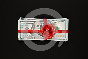 Money us dollars cash gift with red ribbon on black background. American Dollar 100 banknote gift profit concept