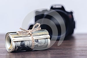 Money US dollars in a roll tied with a rope near the camera. Salary for the work of a photographer