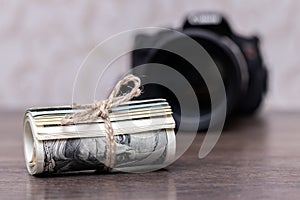 Money US dollars in a roll tied with a rope near the camera. Salary for the work of a photographer