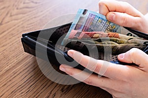 Money and wallet hold in hand. Spending Euro banknotes. Concept image for economy crisis spending review measure to avoid debit