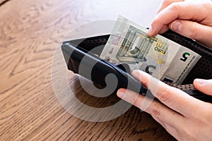 Money and wallet hold in hand. Spending Euro banknotes. Concept image for economy crisis spending review measure to avoid debit