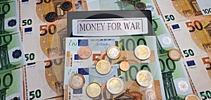Money for war A calculator surrounded by euro bills and coins. The concept of militarization, increased spending on weapons