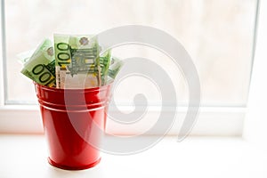 Moneybox, Euro bill in bucket on white window.light background. place for text. a lot of money