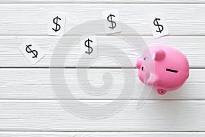 Moneybox in shape of pig and dollar sign on white wooden background top view space for text