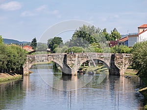 ourists walking along the Roman stone bridge over the river Cabe