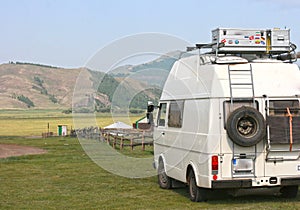 Mongolia / July 28, 2019: Old white vintage van car parked on green hills.