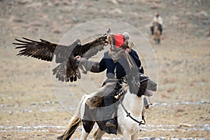 Mongolia. Traditional Golden Eagle Festival. Unknown Mongolian Hunter Berkutchi On Horse With Golden Eagle. Falconry In West M