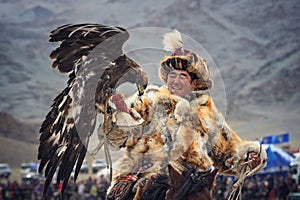 Mongolia. Traditional Golden Eagle Festival. Unknown Mongolian Hunter Berkutchi On Horse With Golden Eagle. Falconry In West Mon