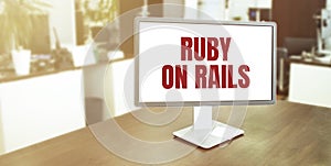 Monitor in modern office with text RUBY ON RAILS on the screen